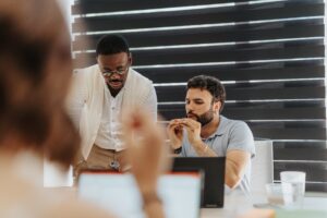 Two men speaking at a desk| FourthRev